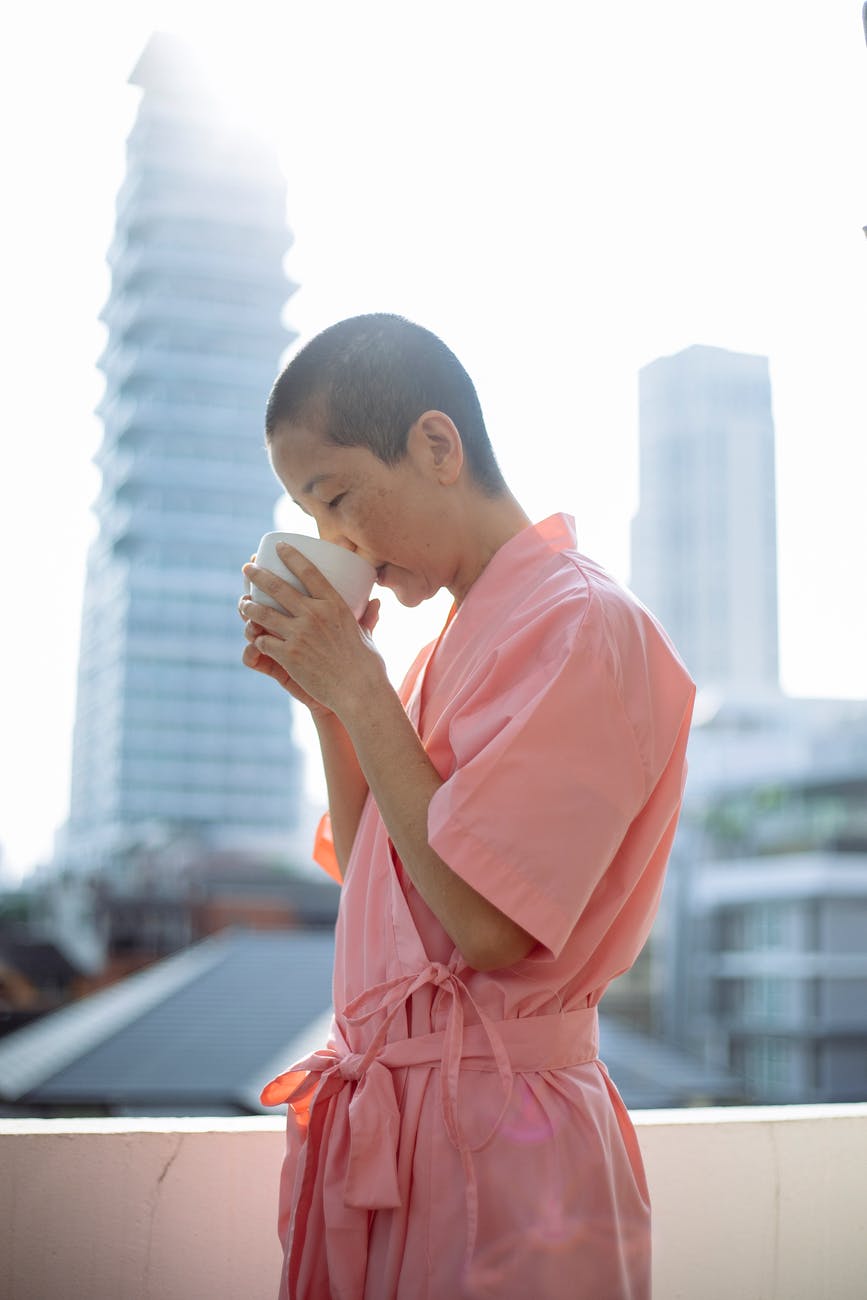 short haired asian woman suffering from cancer drinking tea