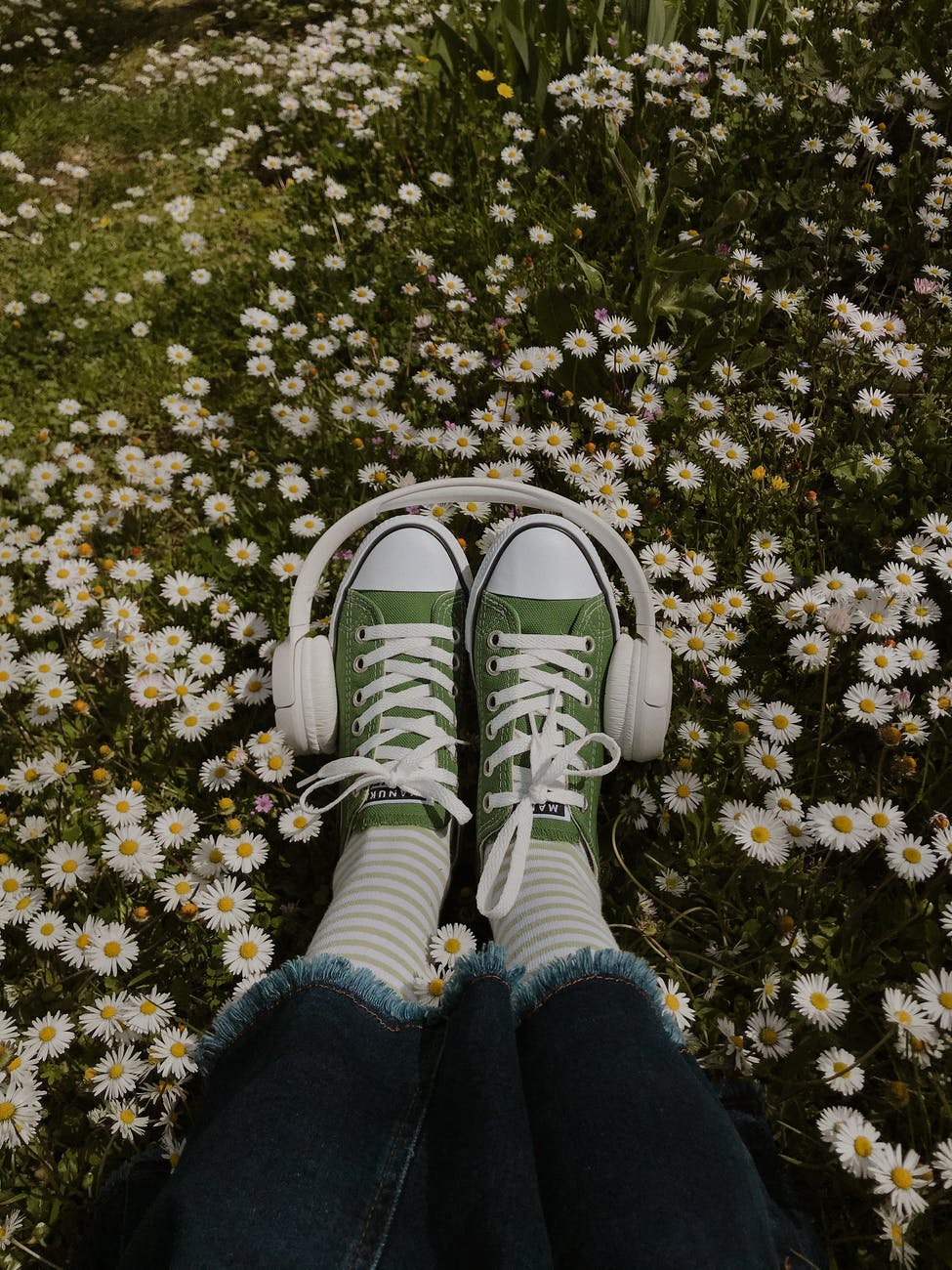 woman chilling in meadow with headphones on legs