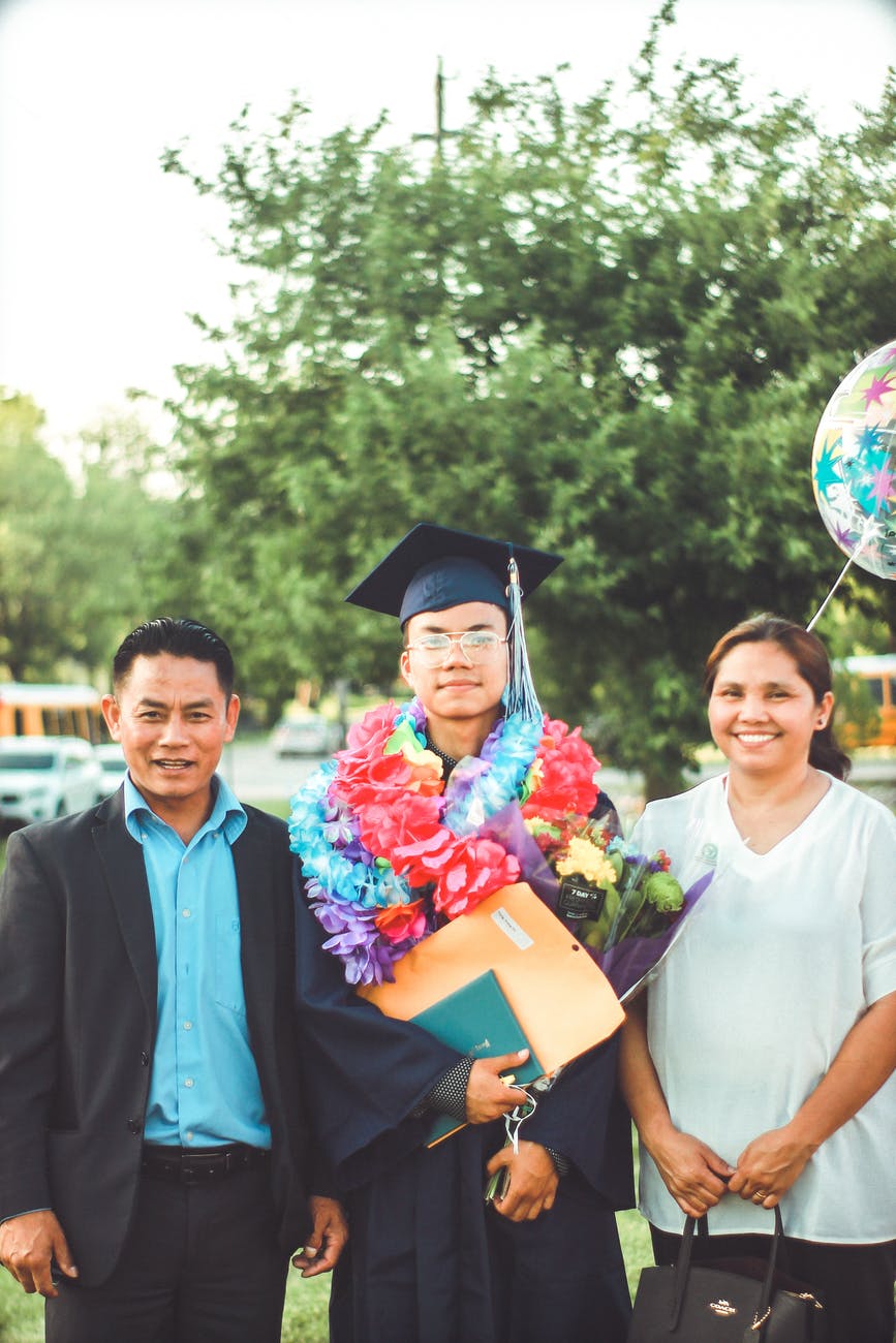 photo of a man wearing academic gown together with his parents